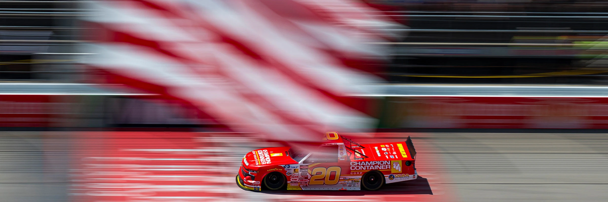 No. 20 Champion Container Craftsman Truck at speed past the American flag